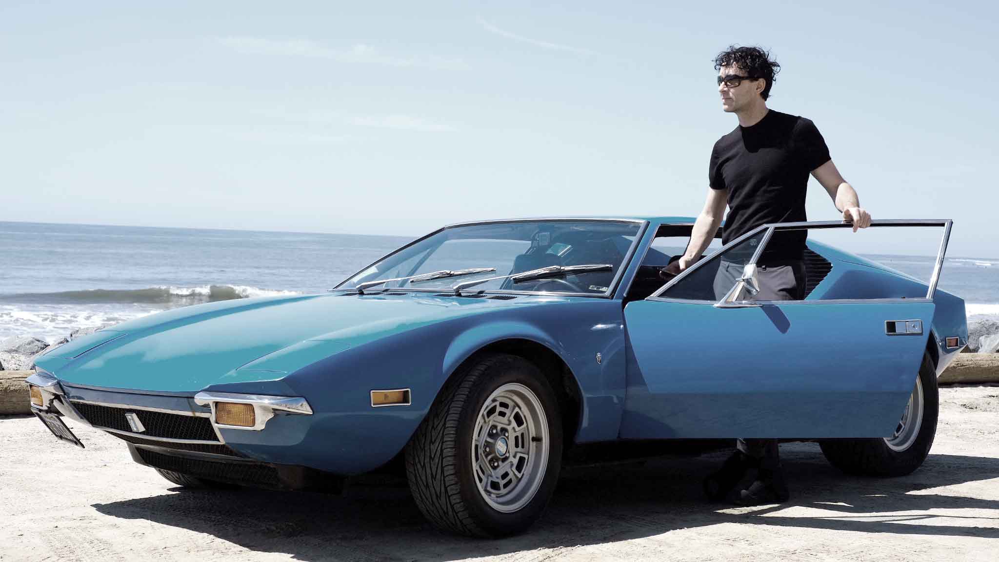 A man beside a blue Pantera on the coast